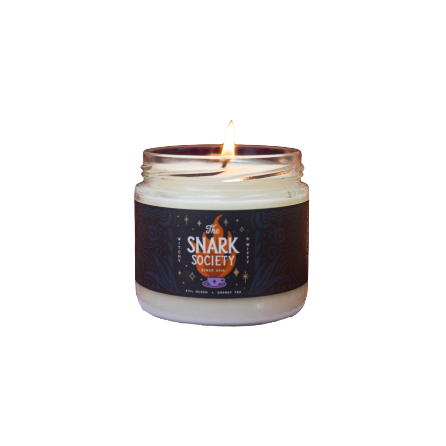 A lifestyle image of the snark society candle being lit, sitting on a purple pedestal surrounded by other candles, candy, spiders, and webbing on an orange foreground and velvet purple background