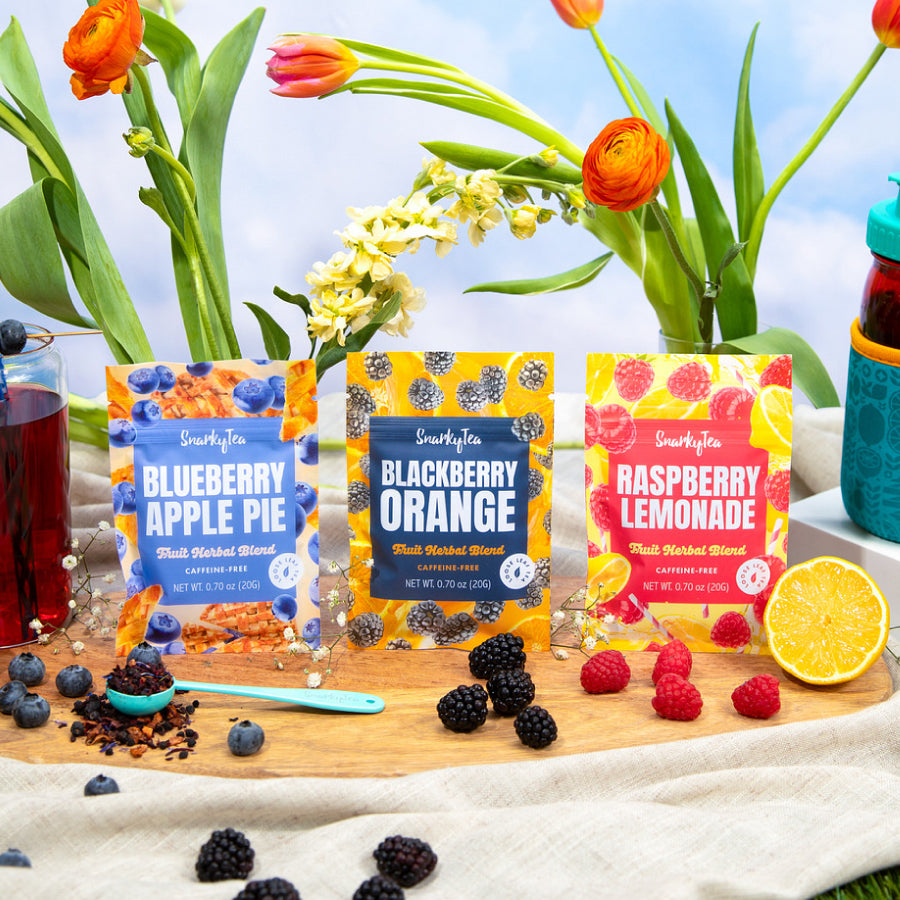 Three packages of Caff-Free herbal tea blends, each with a different flavor: Blackberry Orange, Raspberry Lemonade, and Blueberry Apple Pie. Each package has a colorful design featuring the respective fruit associated with the flavor.