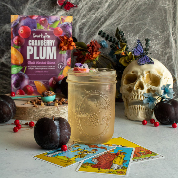 Snarky Tea Cranberry Plum Fruit Herbal Blend loose-leaf tea 60 gram pouch with illustrated cranberries, plums, and fruit on a purple background; caffeine-free herbal tea; bag is sitting on a white background