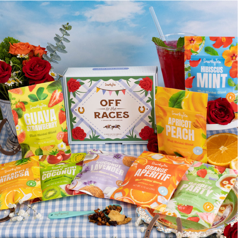 Off to the Races sampler box surrounded by 20g samples of teas inside the sampler (Pineapple Mimosa, Guava Strawberry, Coconut Lavender, Orange Aperitif, Garden Party, Apricot Peach, Cherry Kiwi Coconut, Hibiscus Mint)