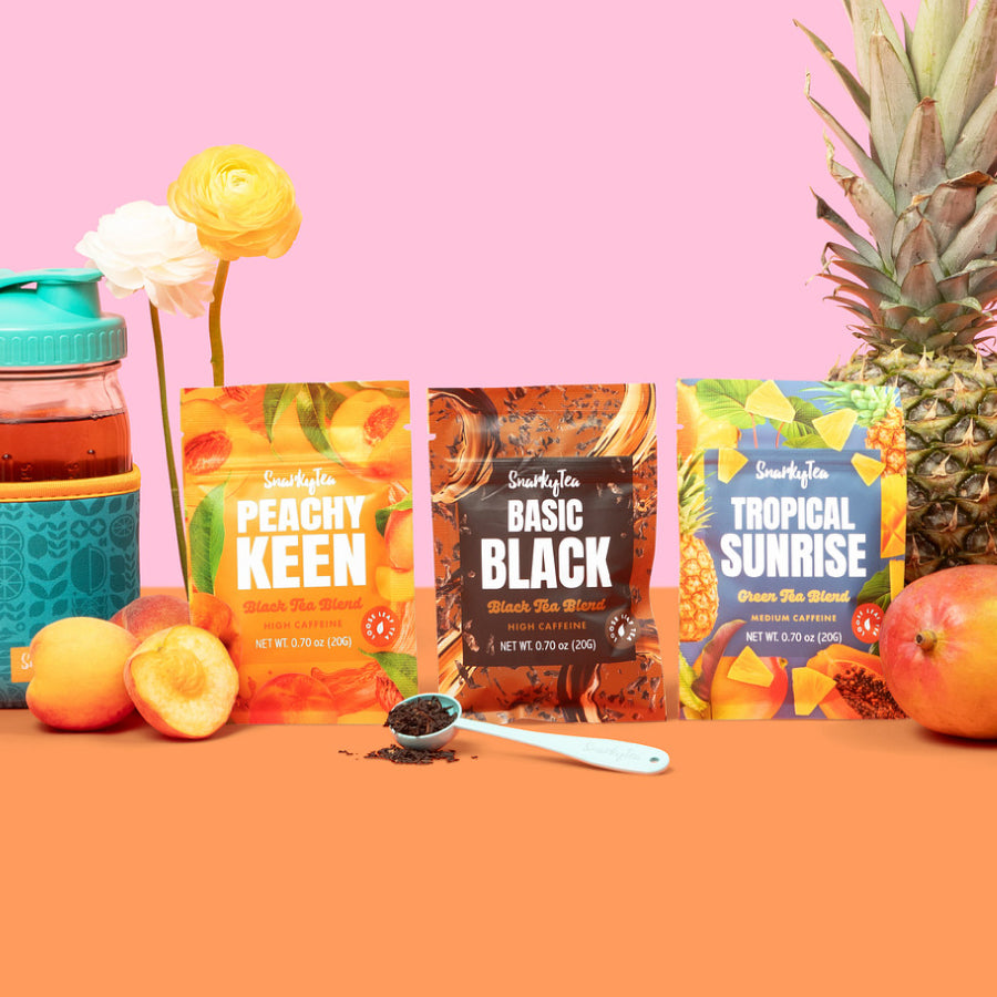 Three Snarky Tea packages labeled 'Peachy Keen', 'Basic Black', and 'Tropical Sunrise' on a white background.