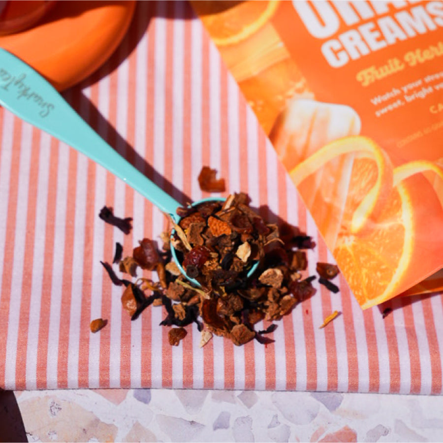 Packaging of Orange Creamsicle fruit herbal blend tea by SnarkyTea showing images of orange slices and bright yellow color theme.