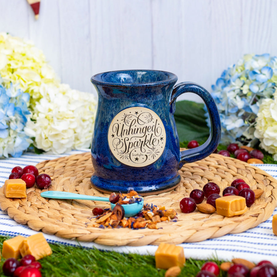 Blue mug with 'Unhinged Sparkle' text on a white background